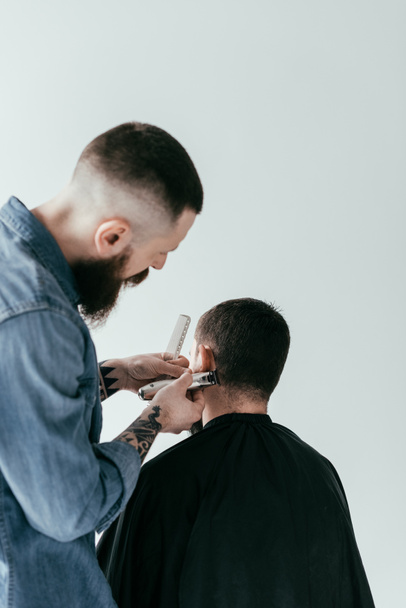 Rückansicht Friseur rasiert Kundenhaare beim Friseur isoliert auf Weiß - Foto, Bild