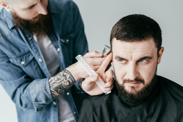 peluquero afeitar el cabello del cliente con la máquina de afeitar en la barbería aislado en blanco
 - Foto, Imagen