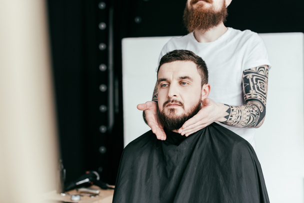 image recadrée du coiffeur coiffant barbe du client au salon de coiffure
 - Photo, image