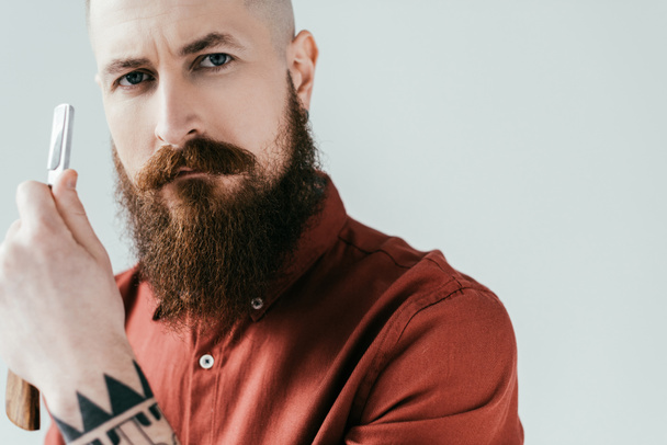 portrait of bearded handsome barber holding razor isolated on white - Foto, Bild