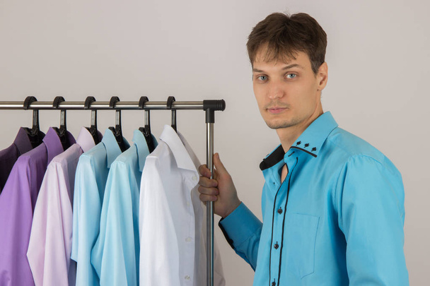 Joven sexy hombre elige una camisa de una variedad de camisas colgando
  - Foto, Imagen