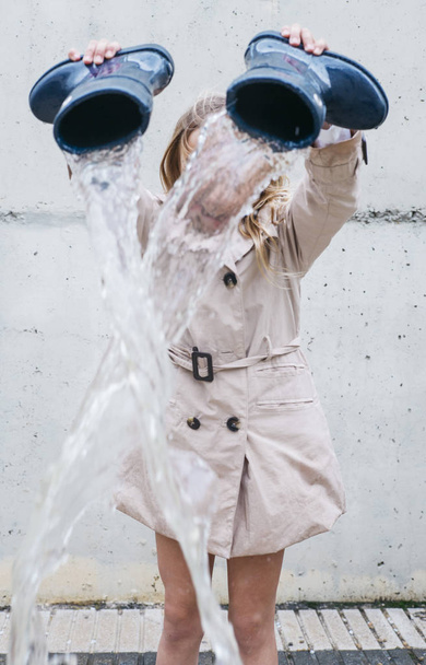 Κορίτσι ρίχνει νερό από της εκκίνησης και παίζοντας στη βροχή. - Φωτογραφία, εικόνα