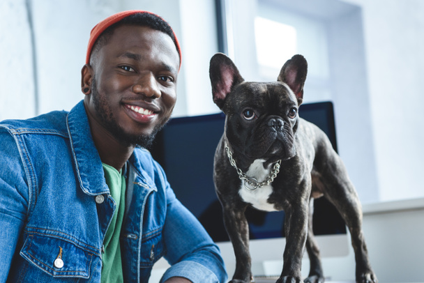Young man with French bulldog by computer screen - Foto, imagen