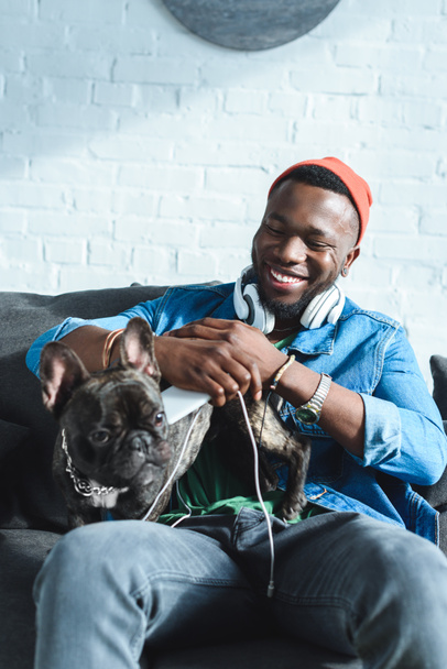 African american man in headphones hugging French bulldog - Фото, зображення