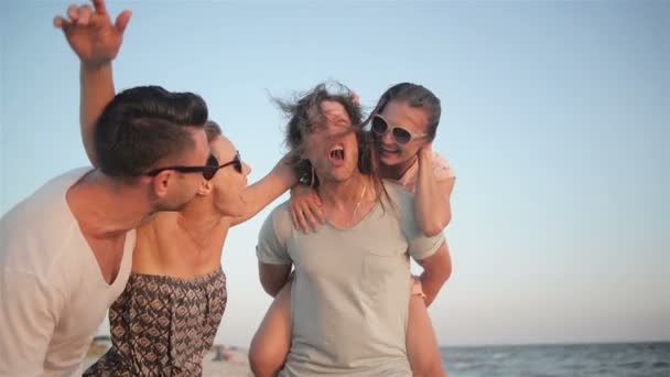 Δύο ζευγάρια γελώντας κοντά στη θάλασσα κατά τη διάρκεια του καλοκαιριού. Υπαίθρια πορτρέτο του ευτυχισμένη ομάδα νέους φίλους να απολαμβάνουν διακοπές στην παραλία. - Πλάνα, βίντεο