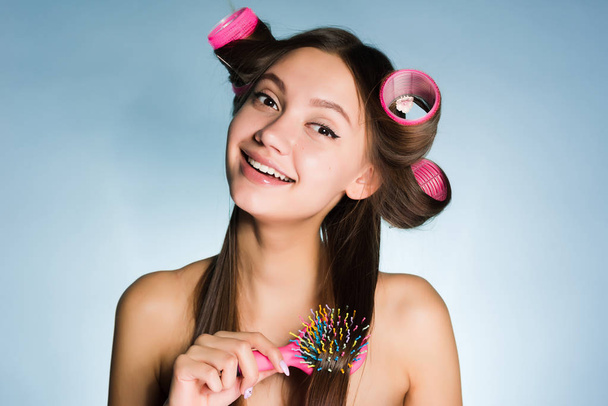 happy beautiful girl doing a hairstyle with a comb and curler, smiling - 写真・画像