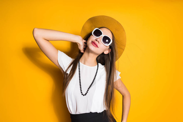attractive stylish girl model in hat and black sunglasses posing, in white blouse - Фото, изображение