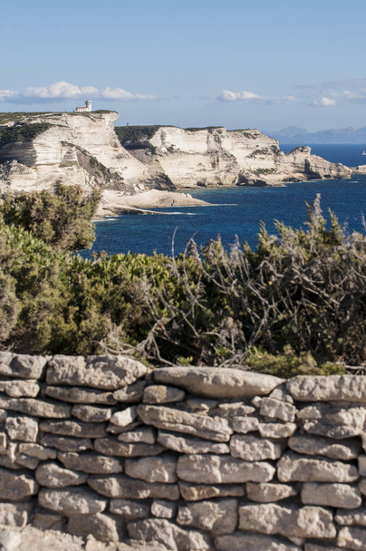 Corsica: un muro di pietra e le scogliere bianche mozzafiato di Bonifacio nel parco marino Bouches de Bonifacio, riserva naturale istituita nel 1993, con vista sul faro di Capo Pertusato
 - Foto, immagini