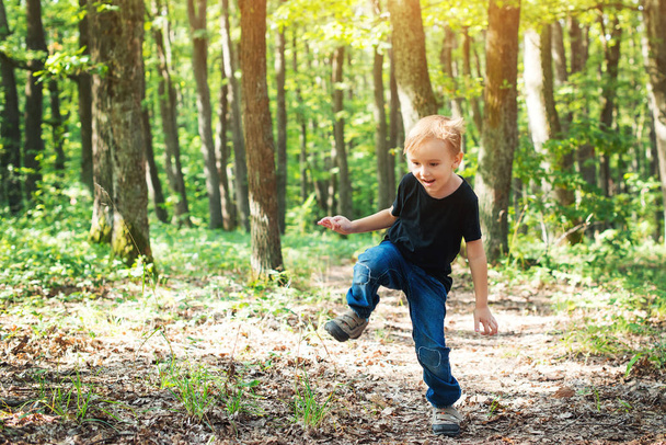 Menino loiro feliz pulando em dia ensolarado na natureza
. - Foto, Imagem