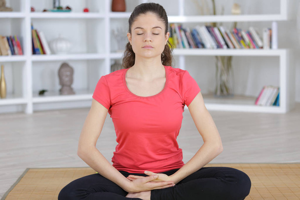 content brunette sitting in lotus pose at home - Foto, Imagen
