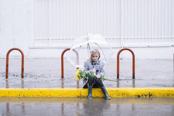 meisje zittend in de straat met een boeket bloemen in r - Foto, afbeelding