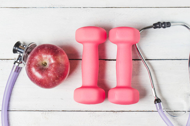 Medical stethoscope and an apple fruit over wooden background. H - 写真・画像