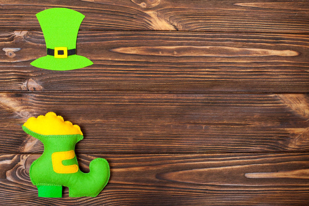 St. Patrick's Day téma színes vízszintes banner. Zöld Manó kalap és a cipő, arany, barna fa háttér. Úgy érezte, creft elemek. Másolja a hely. Az üdvözlőlap, szerencsekívánat banner - Fotó, kép