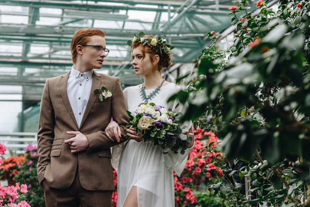 beautiful stylish young bride and groom walking together in botanical garden - Fotoğraf, Görsel