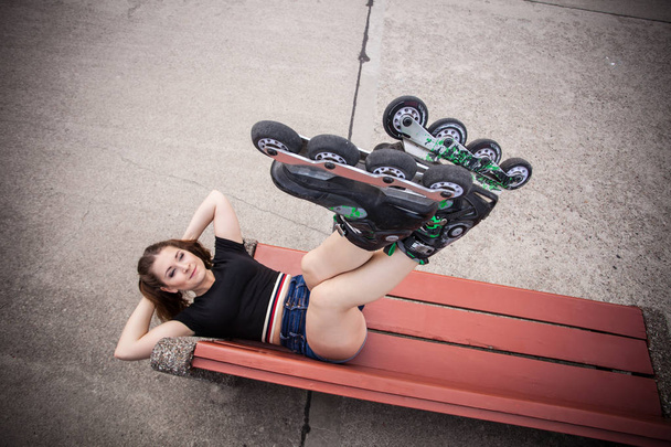 Crazy woman on bench wearing roller skates - Fotoğraf, Görsel