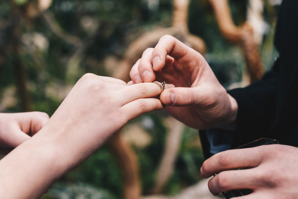 cropped shot of man putting wedding ring on finger of young bride - Fotografie, Obrázek
