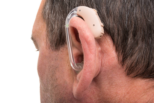Ένα σύγχρονο ακουστικό βαρηκοΐας στο αυτί του ένας νεαρός άντρας της Ευρωπαϊκής.  - Φωτογραφία, εικόνα