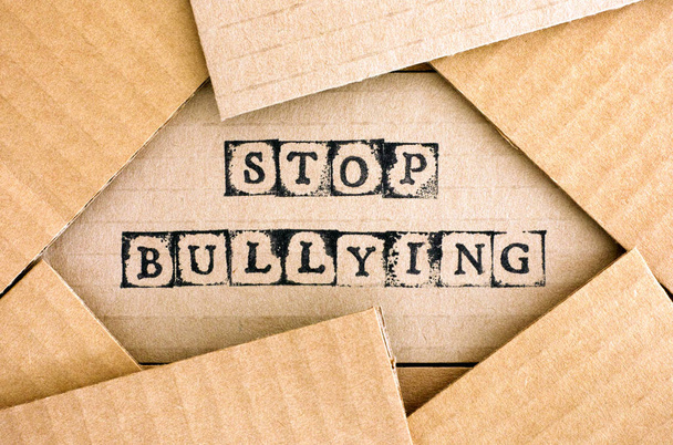 Words Stop Bullying make by black alphabet stamps on cardboard - Foto, afbeelding