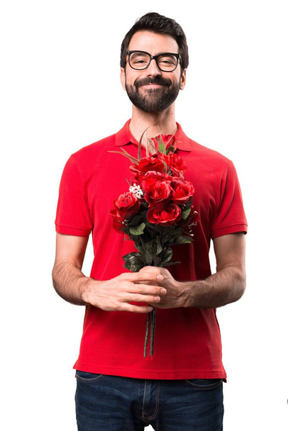Happy handsome man holding flowers over white background - Foto, imagen