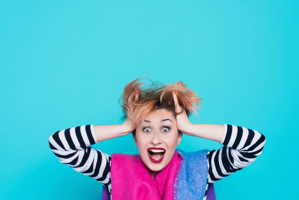 girl with red hair laughing holding his head. Tangled hair. positive emotions. Studio shot. Blue  background - Foto, Imagen