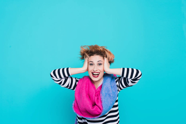girl with red hair laughing holding his head. Tangled hair. positive emotions. Studio shot. Blue  background - Фото, изображение