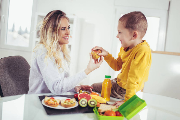 Feliz joven con su hijo desayunando
 - Foto, imagen