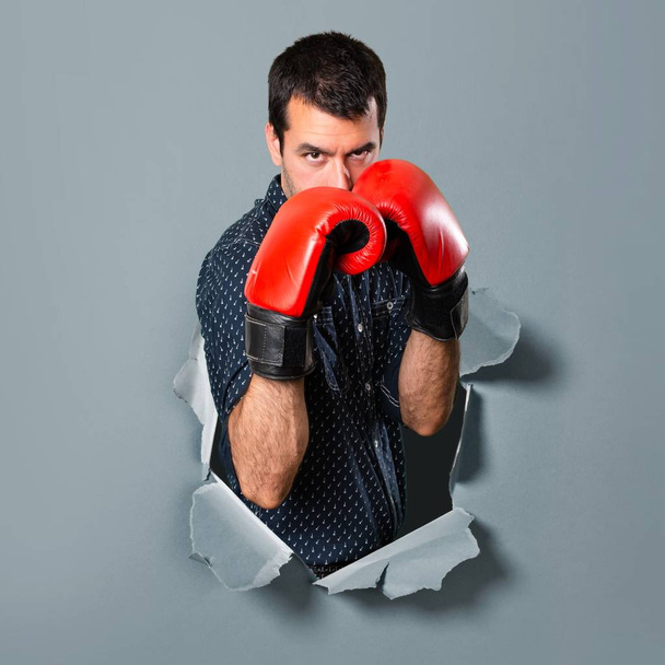 Morena hombre con guantes de boxeo a través de un agujero de papel
 - Foto, imagen
