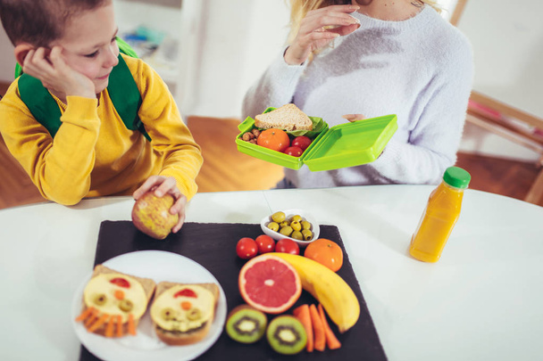 Матері прийняття сніданку за своєю дитиною в ранкові і закуска для школи  - Фото, зображення