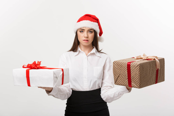Χριστούγεννα Concept - νέοι ευτυχισμένη καυκάσιος γυναίκα με καπέλο santa επιλέγοντας κουτιά δώρων με αντίγραφο χώρο στην πλευρά. - Φωτογραφία, εικόνα