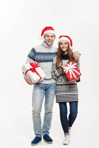 Weihnachtskonzept - junges bezauberndes Paar mit Geschenken auf weißgrauem Hintergrund. - Foto, Bild