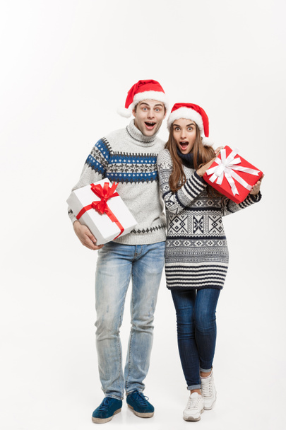Kerst Concept - jonge schattige paar houden presenteert geïsoleerd op wit grijze achtergrond. - Foto, afbeelding