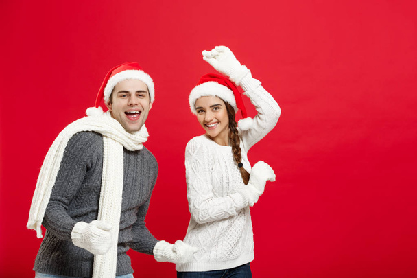 Christmas concept - Happy young couple in sweatesr celebrating christmas with playing and dancing - Foto, Imagen