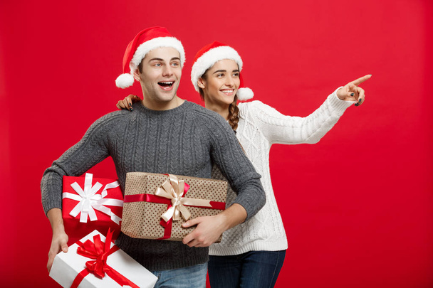 Christmas Concept - Young attractive couple holding a lot of presents enjoy shopping and celebrating in Christmas day - Photo, Image