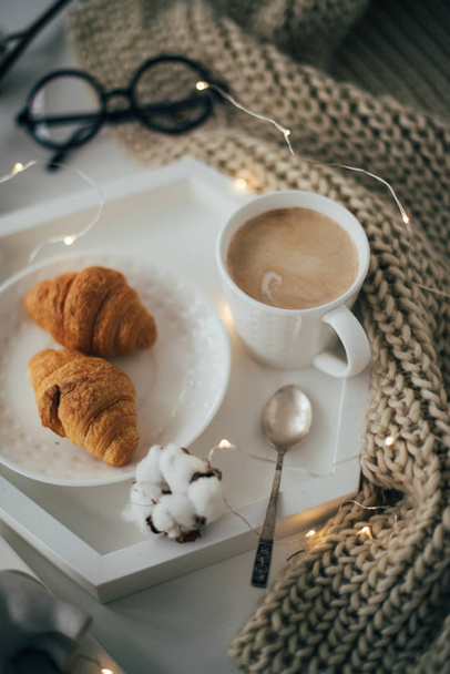 Затишний домашній сніданок, тепла ковдра, кава і круасан на білому
 - Фото, зображення