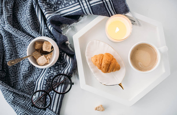 gemütliches Frühstück zu Hause, warme Decke, Kaffee und Croissant auf weiß - Foto, Bild