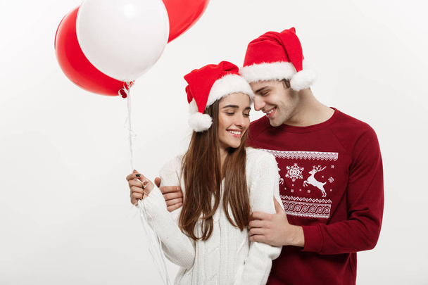 Weihnachtskonzept - junge Freundin mit Luftballon umarmt und spielt mit ihrem Freund und überrascht ihn an Weihnachten - Foto, Bild