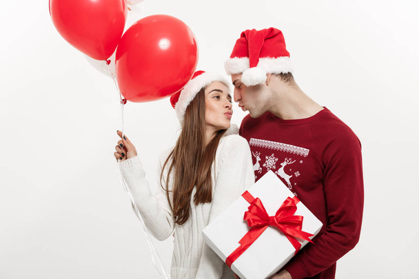 Christmas Concept - Young girlfriend holding balloon is hugging and playing with her boyfriend doing a surprise on Christmas - Photo, Image
