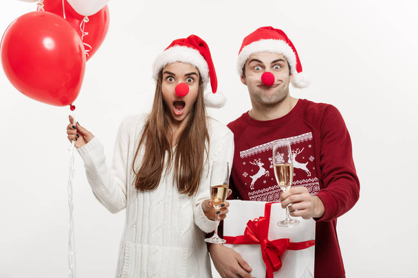 Christmas Concept - Young caucasian couple holding gifts,champagne and balloon making funny face on Christmas - Fotoğraf, Görsel