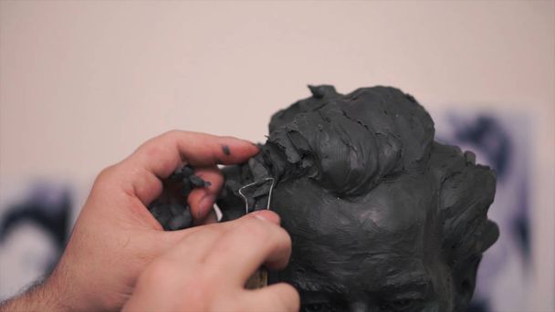 Um escultor que trabalha em sua escultura de barro em sua oficina. Clipe. Homem corta um molde de argila
 - Foto, Imagem
