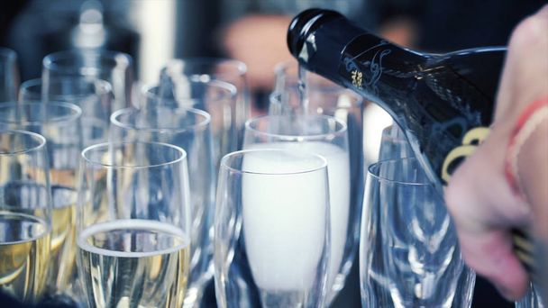 Versare lo champagne in un bicchiere in piedi sul tavolo. Clip. Lo champagne viene versato nei bicchieri
 - Foto, immagini