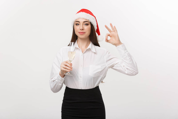 Christmas Celebration - Young beautiful business woman celebrating christmas with glass of champagne and showing ok sign.  - Photo, image