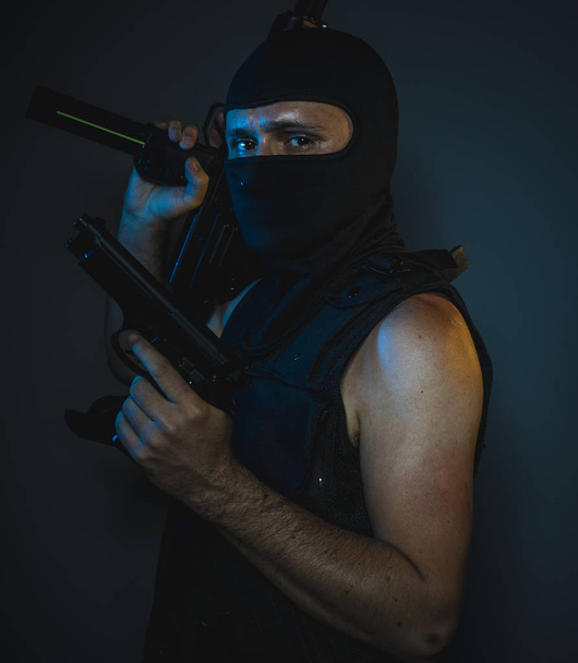 hit man, armed and dangerous man with balaclava and bulletproof vest, concept killer contract - Fotó, kép