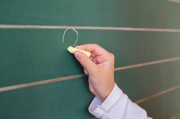 Ученица первого класса, девочка, пишущая на зеленой доске на школьном уроке
 - Фото, изображение