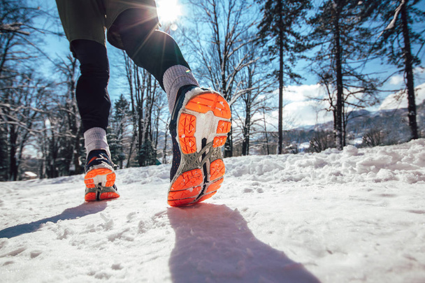  Крупним планом чоловічі ноги бігають по зимовій засніженій дорозі
  - Фото, зображення