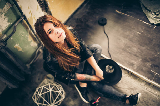 portrait of young fashion woman with red hair and tattoo in black clothes sitting on floor at vintage style room.  - Foto, Imagem