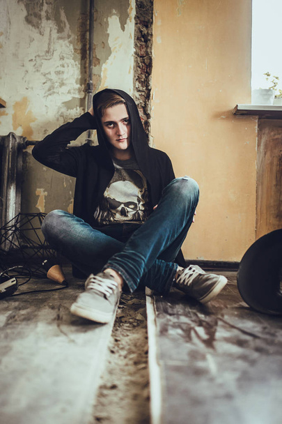 portrait of young fashion man in black clothes sitting on floor at loft style room.  - Foto, immagini