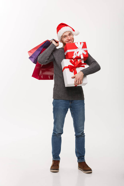 Χριστούγεννα Concept - ελκυστικό νεαρό άνδρα Καυκάσιος Απολαύστε τα ψώνια σας κρατάει πολλά δώρα για την ημέρα των Χριστουγέννων. - Φωτογραφία, εικόνα
