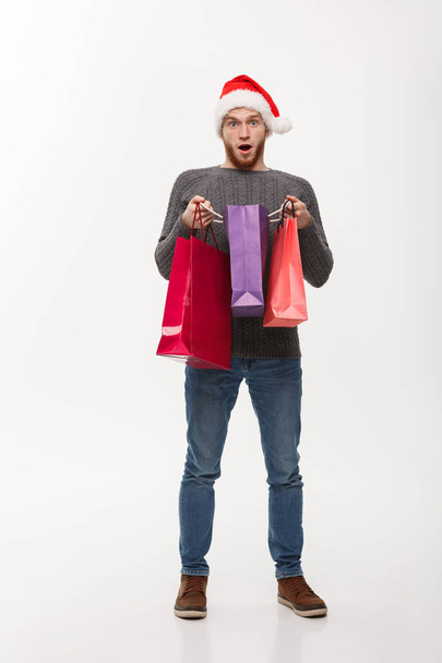 クリスマス コンセプト - ショッピング バッグで魅力的な若い白人男驚くべき衝撃的なギフト. - 写真・画像