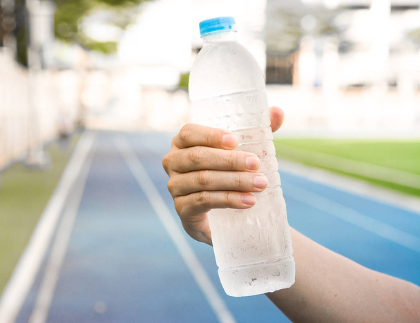 透明ボトルの冷水は refr の 1 つの手で保持しています。 - 写真・画像