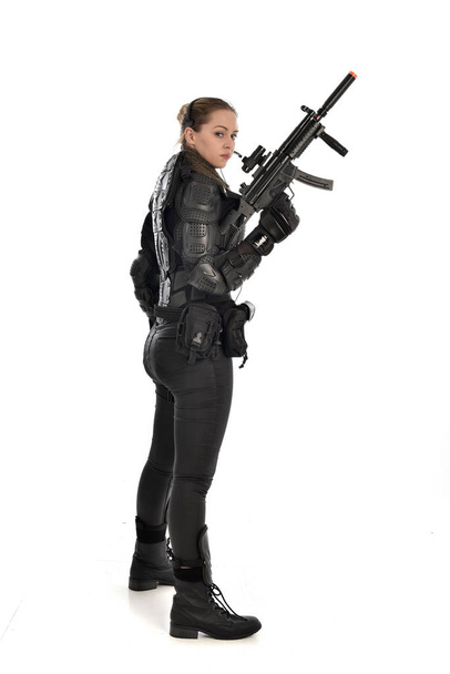 full length portrait of female  soldier wearing black  tactical armour, holding a rifle gun, isolated on white studio background. - Foto, Bild